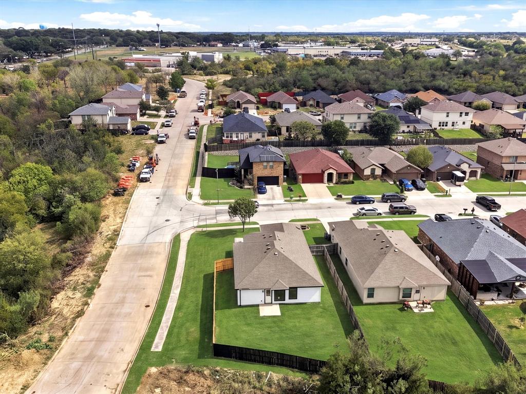 Aerial perspective of a residential neighborhood featuring expansive, manicured lawn space, composition shingle roofing, and established perimeter fencing