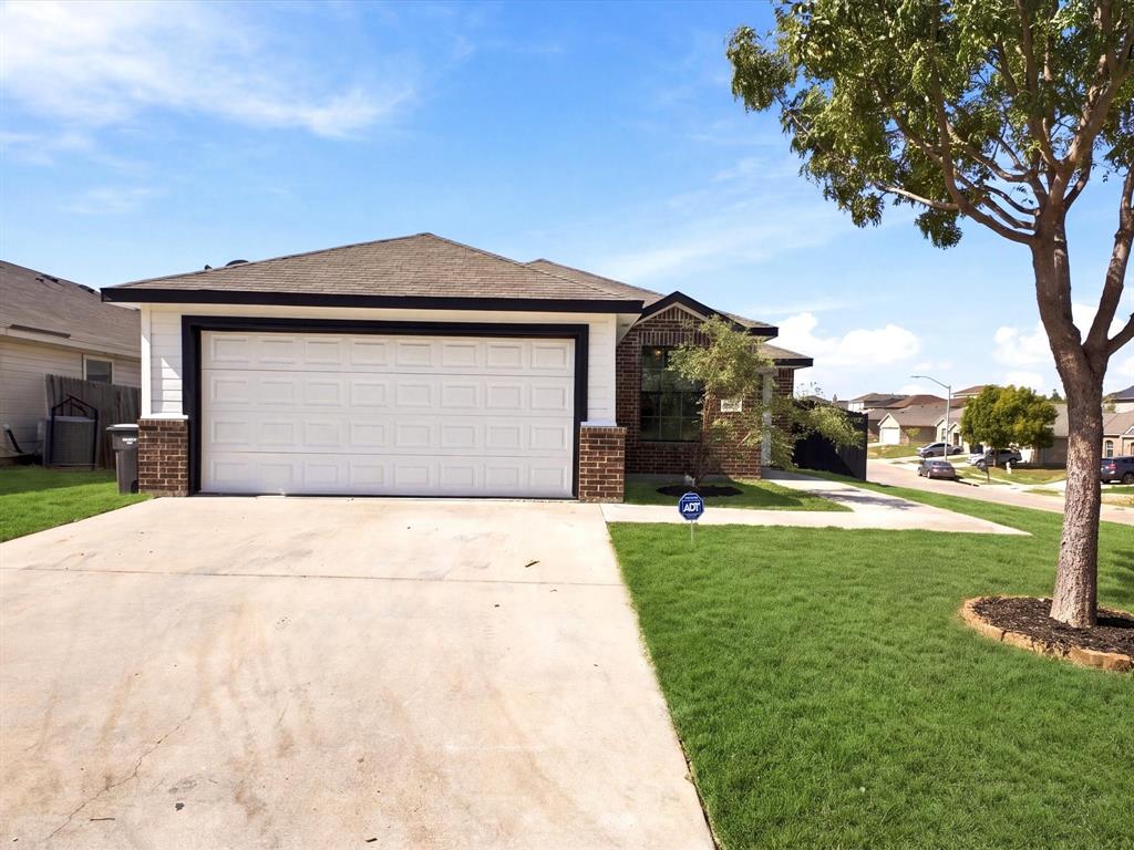 Single-story exterior featuring a brick and composite siding facade, attached two-car garage, concrete driveway, and landscaped front lawn