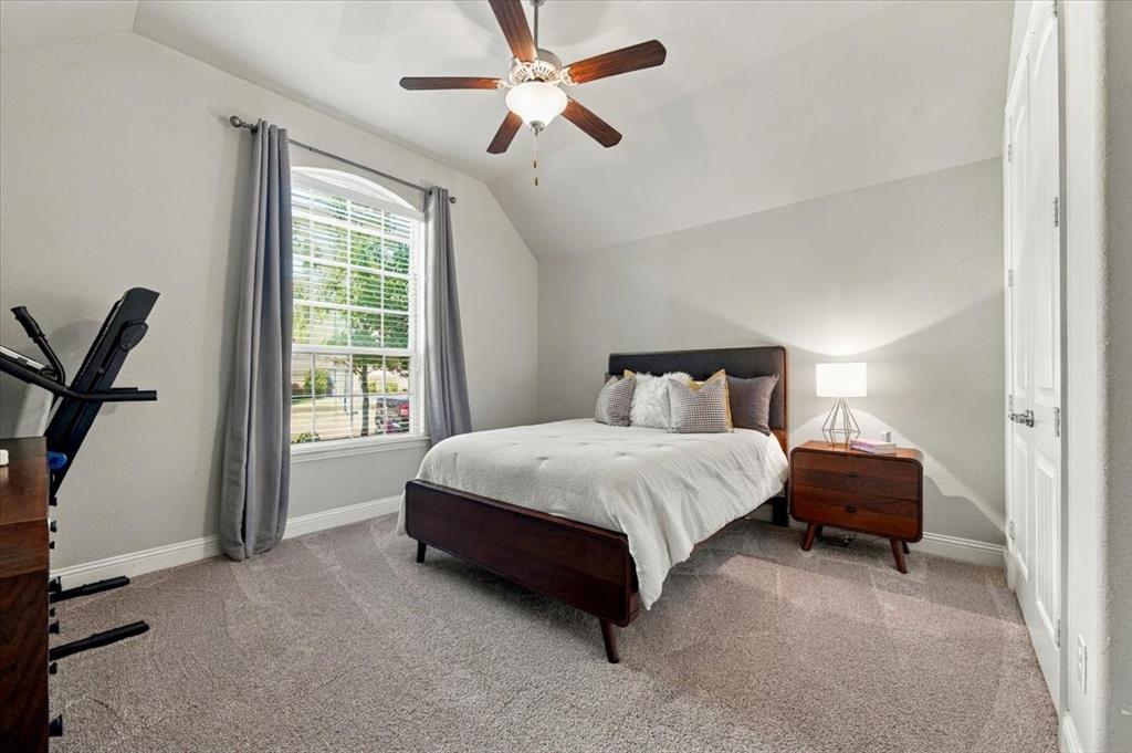 Suite Bedroom features a vaulted ceiling and a ceiling fan with light fixture, and an arched-top window overlooking the front yard. Carpet flooring extends throughout.