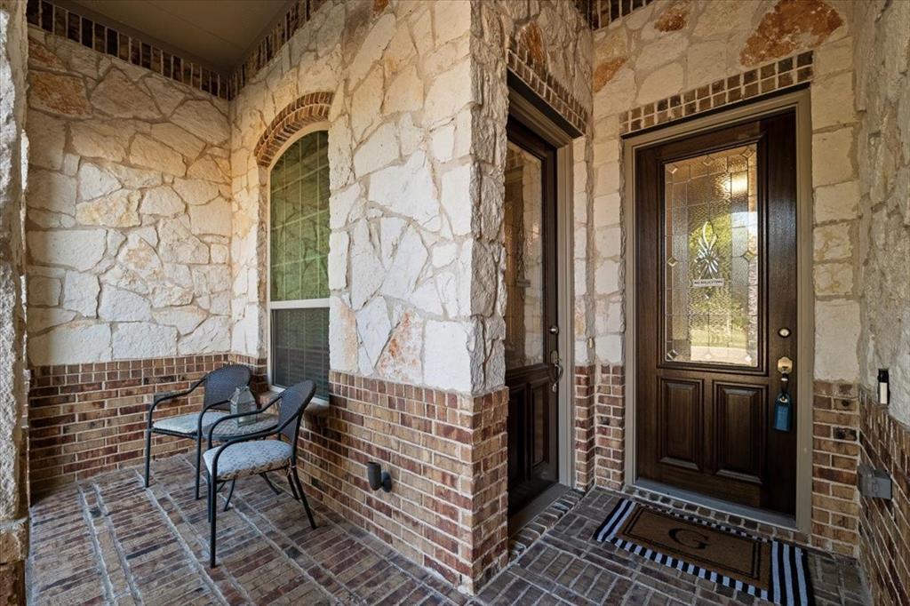 Covered front porch features stone and brick walls, an arched window, a front entry door with decorative glass, and a separate exterior entry to the suite sitting room. Brick flooring extends throughout. Covered front porch features stone and brick walls, an arched window, a front entry door with decorative glass, and a separate exterior entry to the suite sitting room. Brick flooring extends throughout.