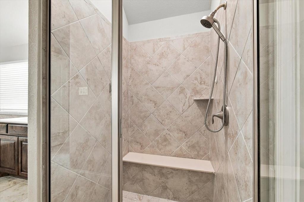 Primary Bathroom features a walk-in shower with a glass enclosure, diagonal tile surround, a built-in bench, a corner shelf, and a handheld showerhead. Ceramic tile flooring extends throughout.