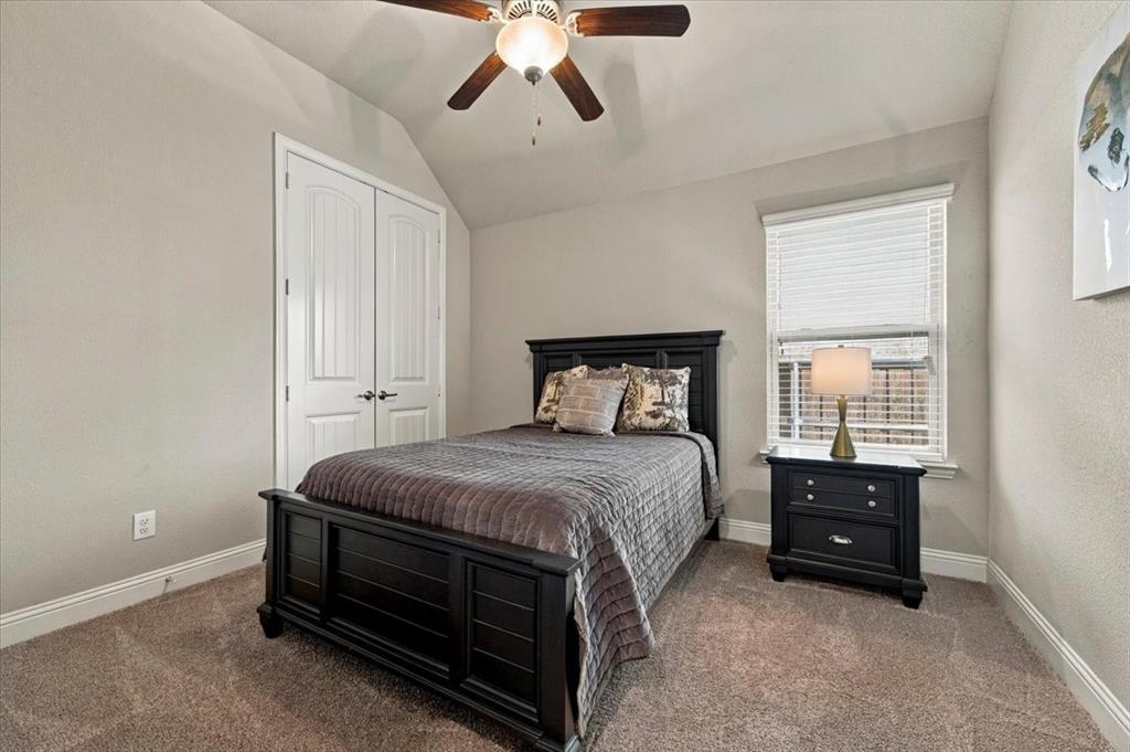 Secondary Bedroom features a vaulted ceiling and a ceiling fan with light fixture, a window, and a double-door closet. Carpet flooring extends throughout.