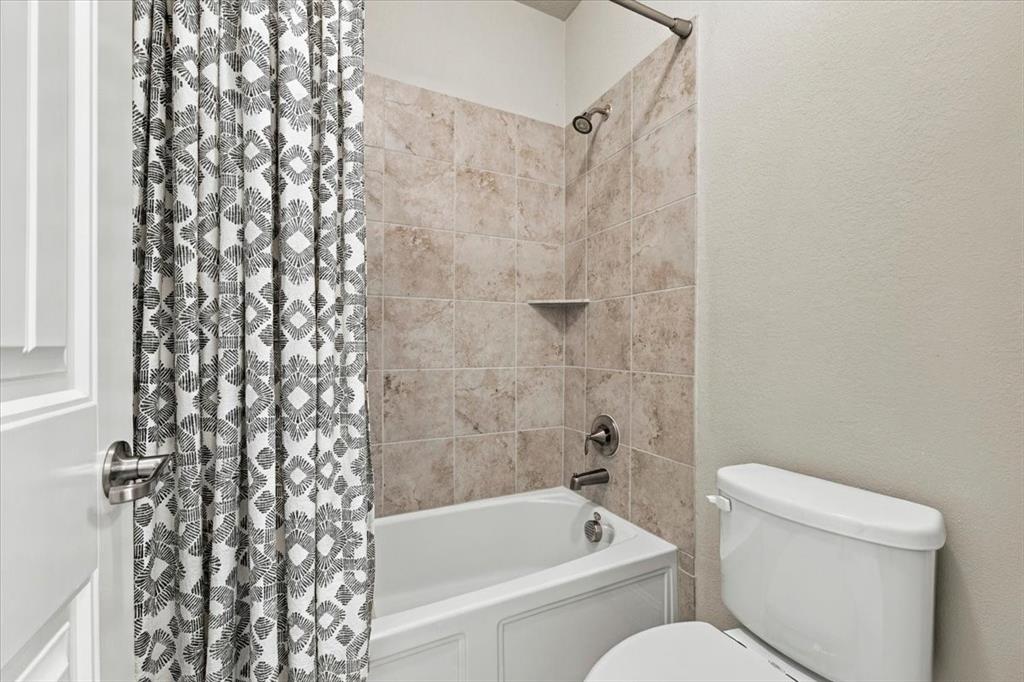 Secondary Bathroom features a separate compartment with a tub/shower combination, tile surround with a corner shelf, and a toilet. Ceramic tile flooring extends throughout.