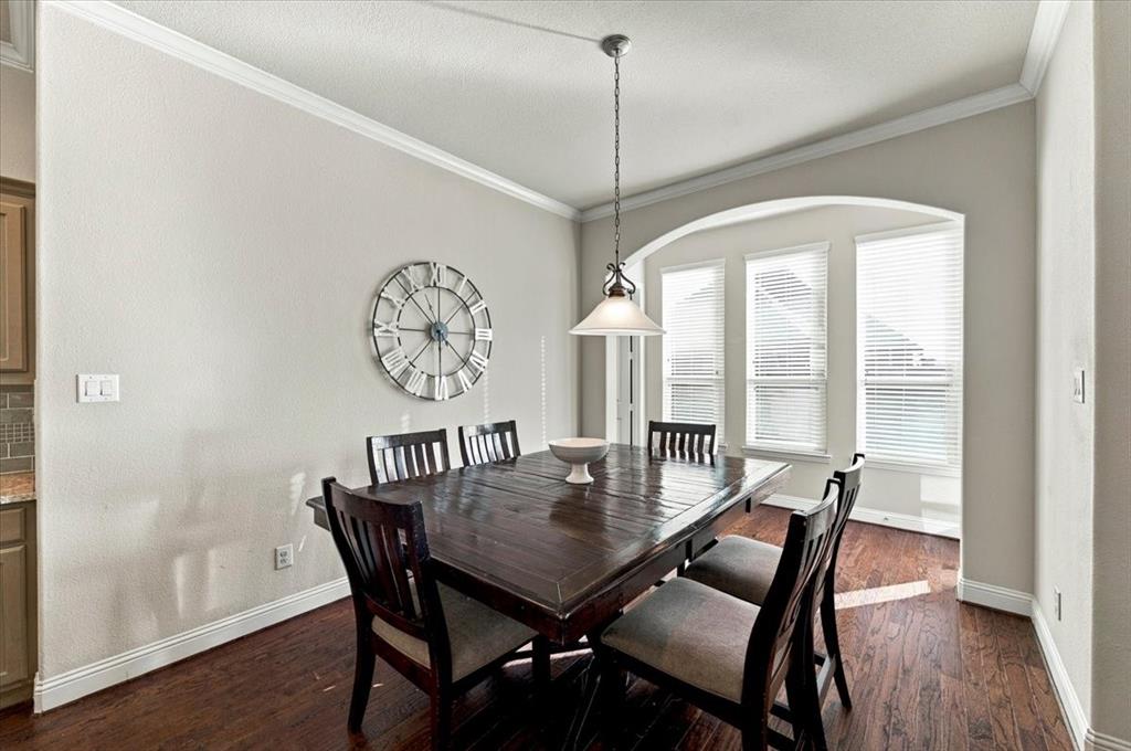Dining Area features crown molding, a pendant light fixture, and an arched alcove with three windows. Wood flooring extends throughout.