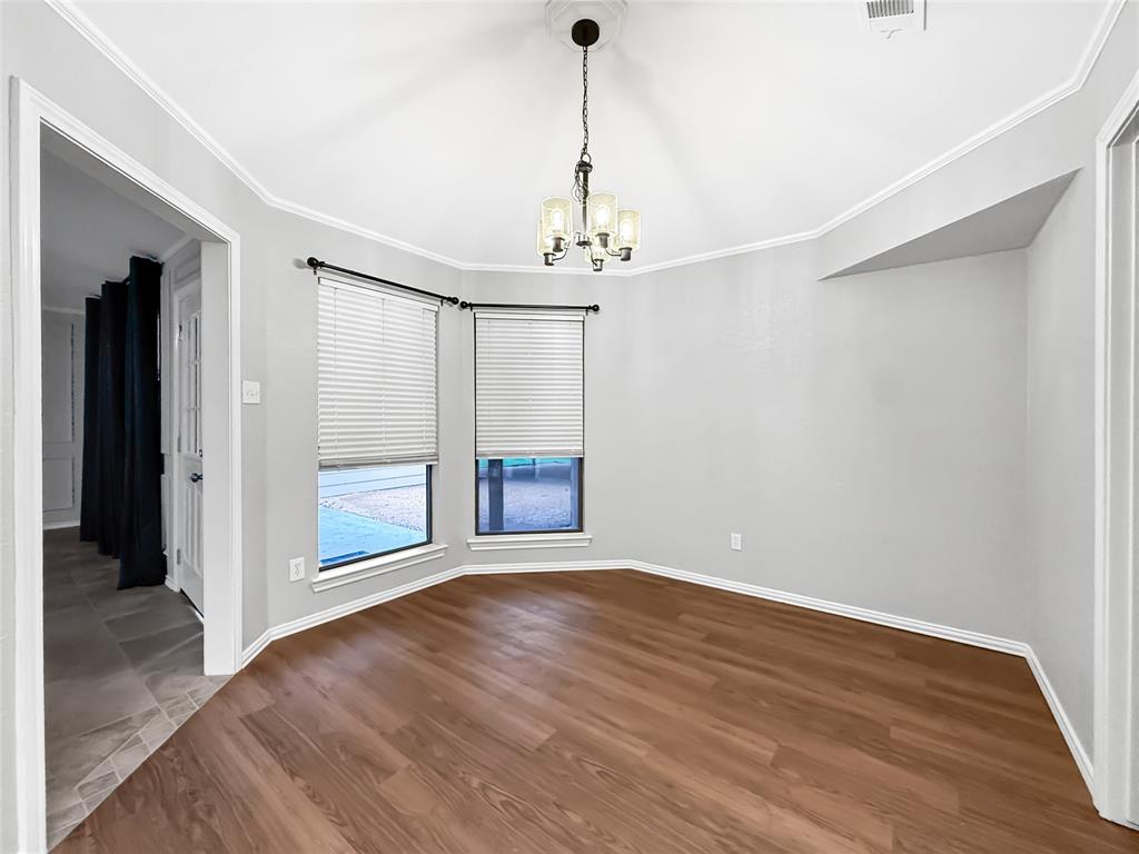 Bay window featuring dual vertical windows, wood-finish flooring, vaulted ceiling, and multi-light hanging chandelier
