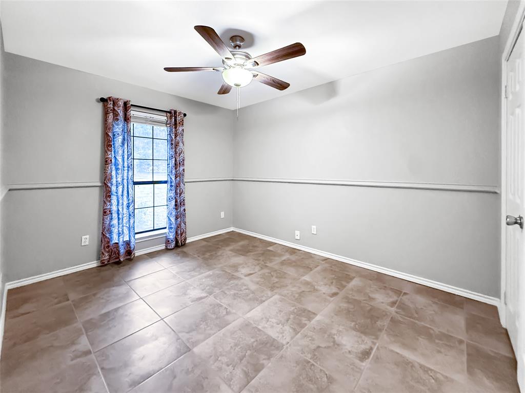Room featuring large-format ceramic tile flooring, neutral wall paint, a chair rail, and a ceiling fan with integrated lighting