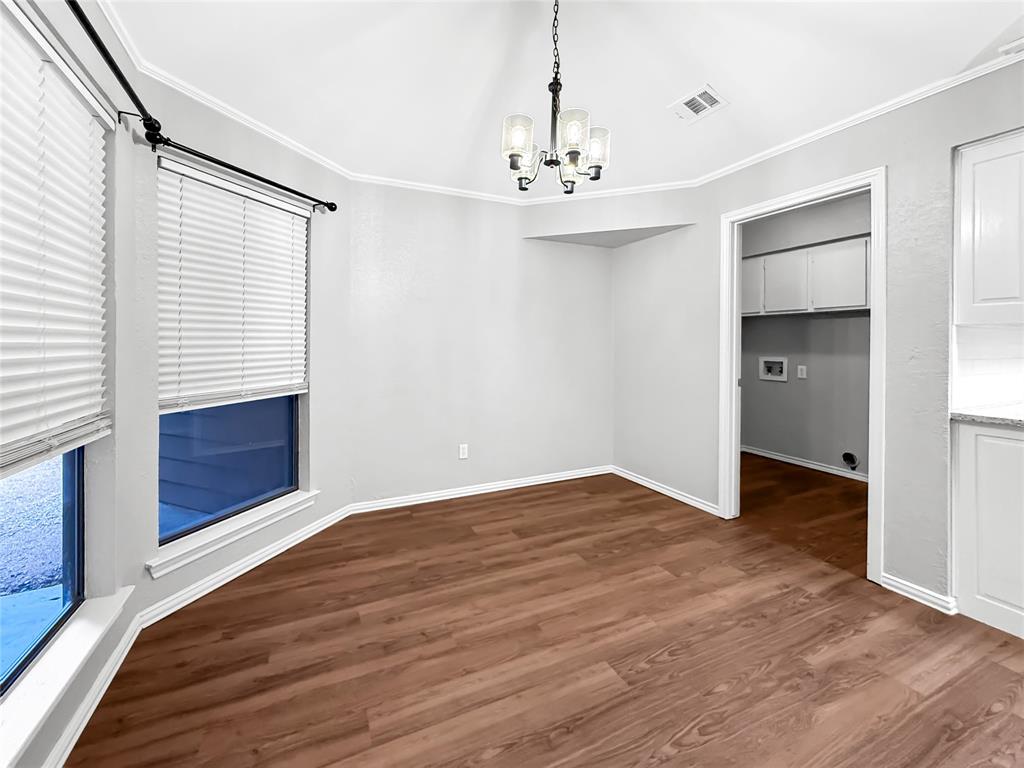 Bay area with multi-pane windows, wood-finish flooring, vaulted ceiling, and an architectural hanging chandelier