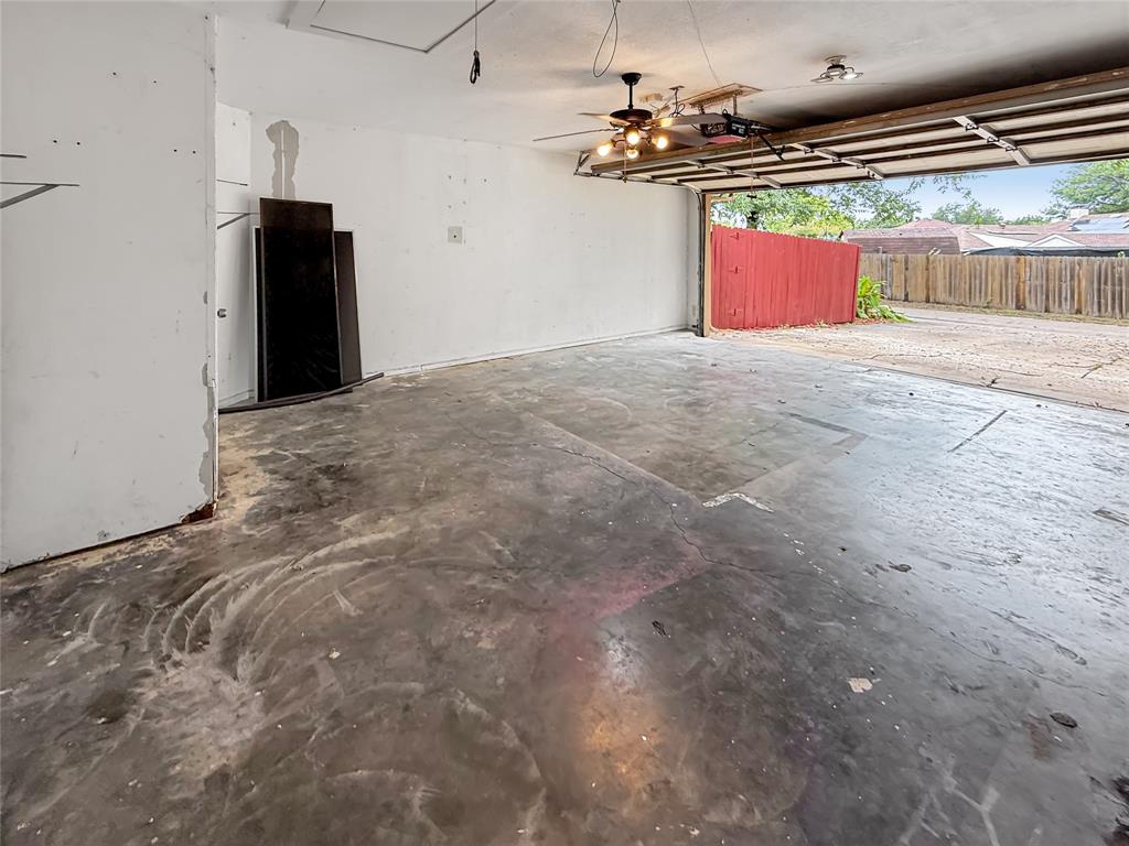 Garage space featuring a concrete floor, ceiling-mounted light fixture, and an automated overhead garage door