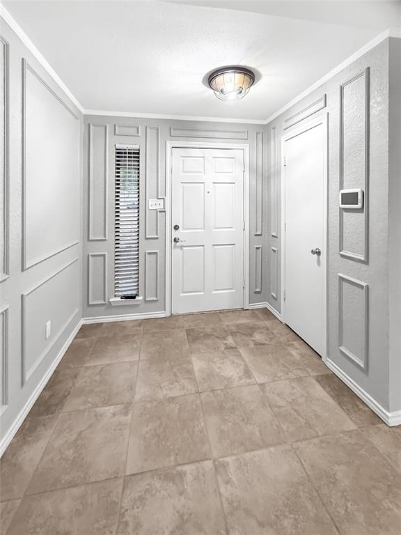 Entryway featuring decorative wall molding, tile flooring, six-panel door, vertical sidelight window, and a flush-mount ceiling fixture