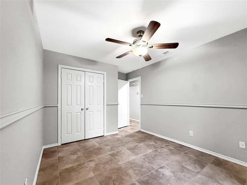Interior room featuring large-format tile flooring, chair rail molding, ceiling-mounted light fixture with fan, and double-door closet