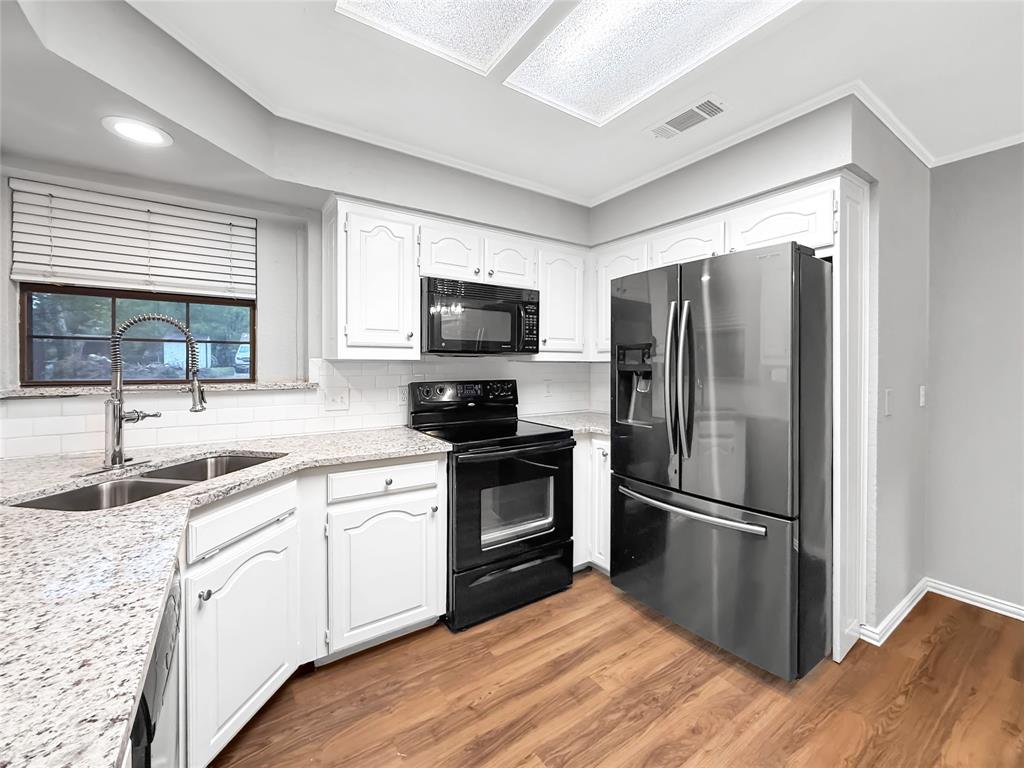 Kitchen featuring white cabinetry, stone-finish countertops, subway tile backsplash, stainless steel finish refrigerator, and wood-finish flooring