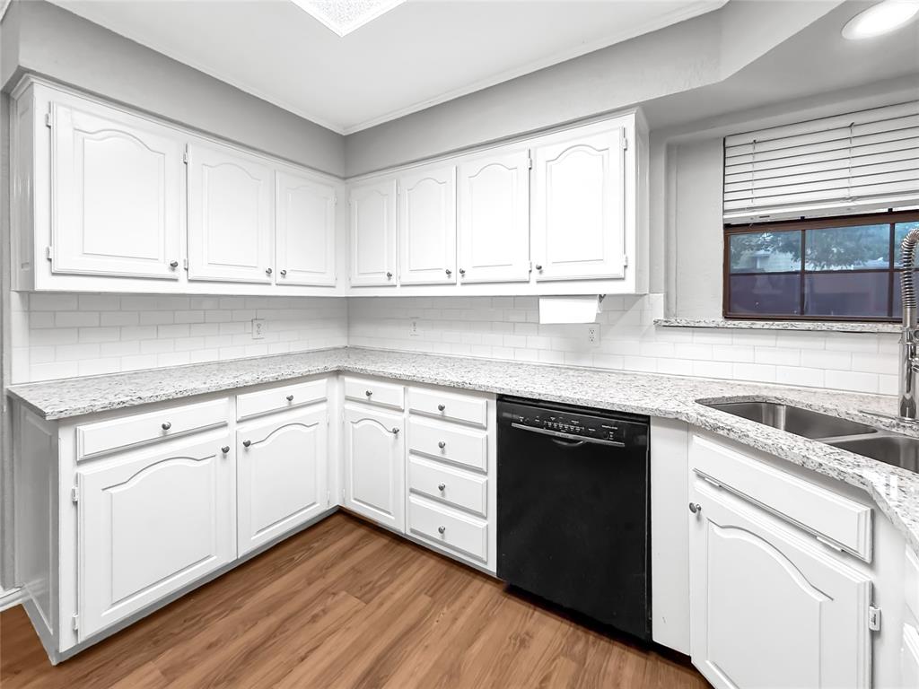 Kitchen featuring white cabinetry, stone-finish countertops, subway tile backsplash, wood-finish flooring, and a stainless steel kitchen faucet