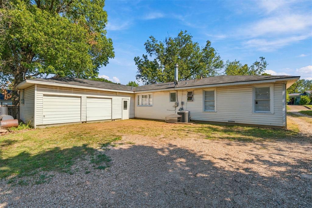 L-shaped exterior featuring horizontal siding, a two-car garage with dual overhead doors, and mature trees
