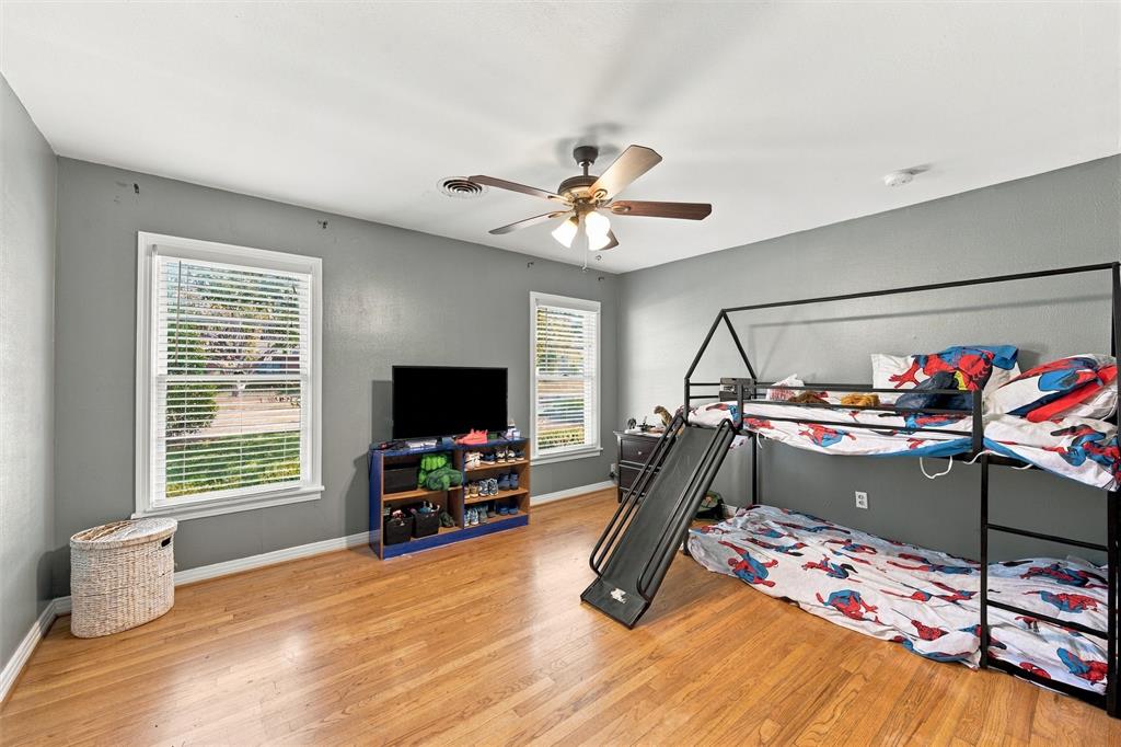 Interior space featuring wood-finish flooring, two windows with horizontal blinds, and a ceiling fan with integrated lighting