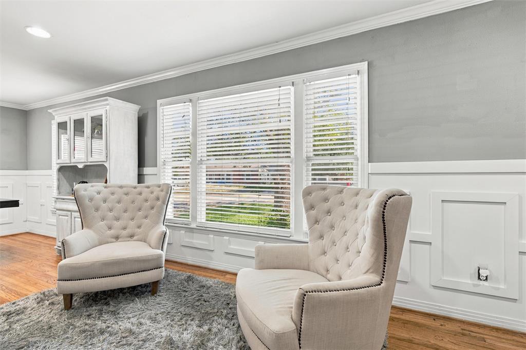 Triple window configuration with white blinds, wood-finish flooring, built-in white china cabinet, and wainscoting