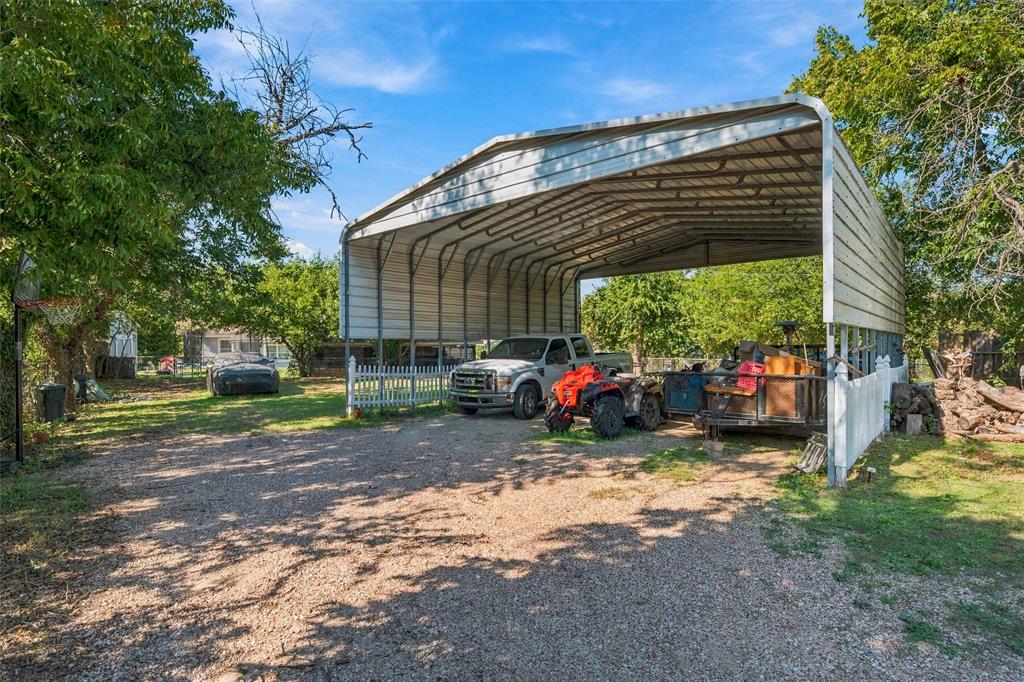Metal-framed carport featuring a corrugated metal roof and gravel surface area