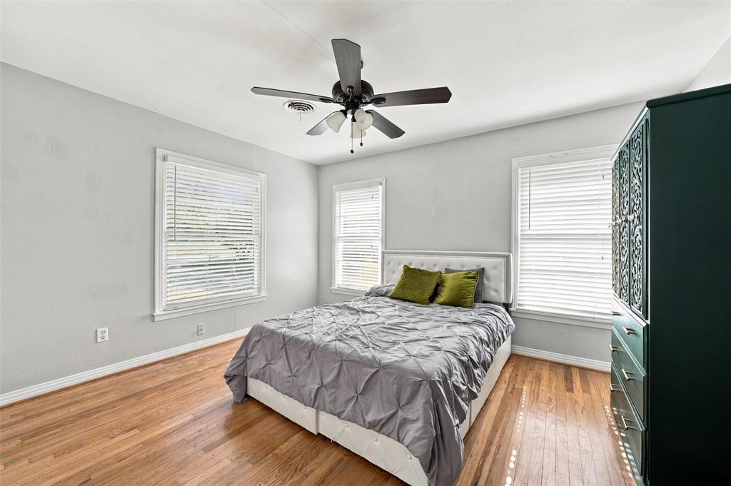 Wood-finish flooring, neutral wall tones, multi-window configuration with horizontal blinds, and a central ceiling fan with integrated lighting