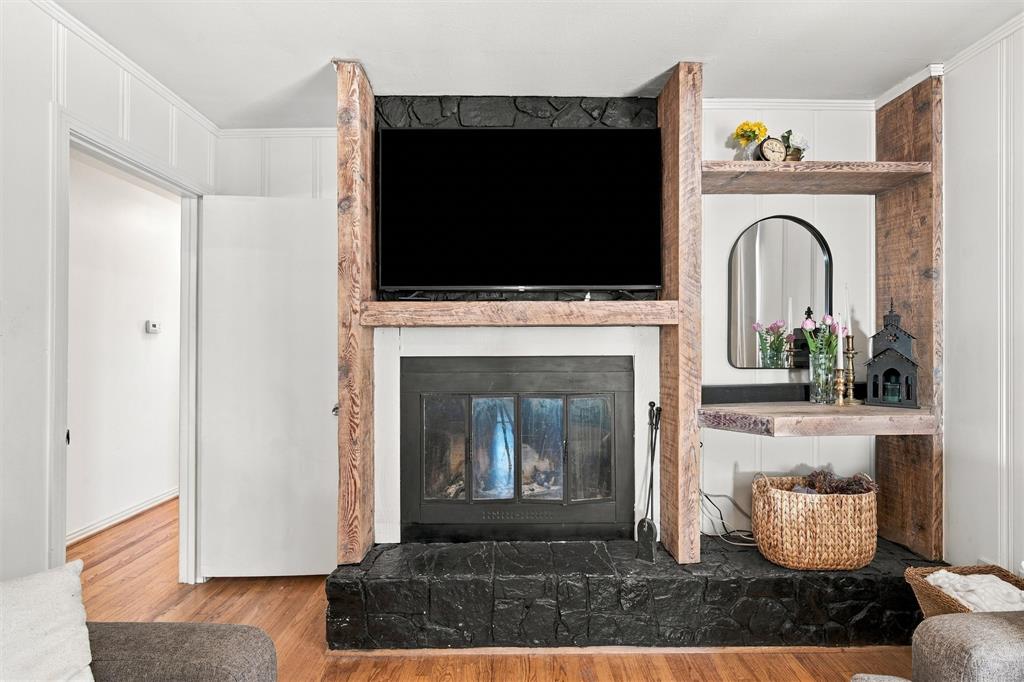 Floor-to-ceiling fireplace feature with dark masonry hearth and surround, integrated reclaimed wood shelving, and wood-finish flooring