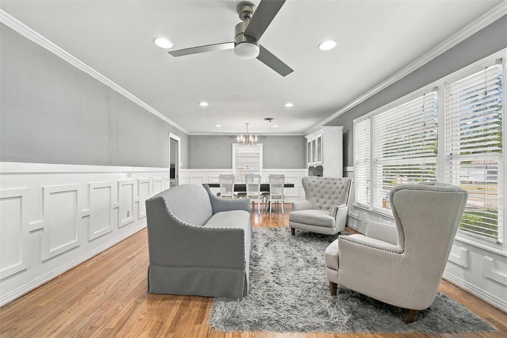 Interior space featuring wood-finish flooring, crisp white wainscoting, a modern ceiling fan, recessed lighting, and large windows with horizontal blinds