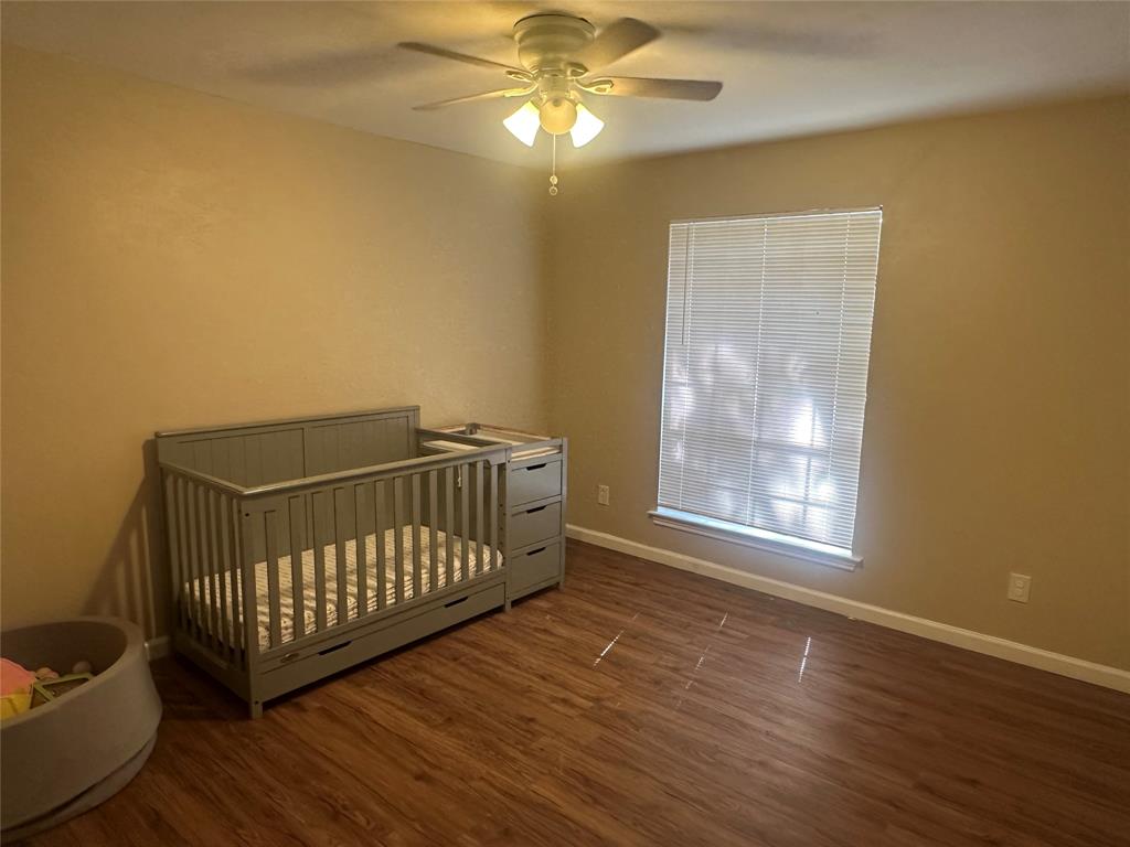 Wood-finish flooring, ceiling fan with integrated lighting, and window with horizontal blinds
