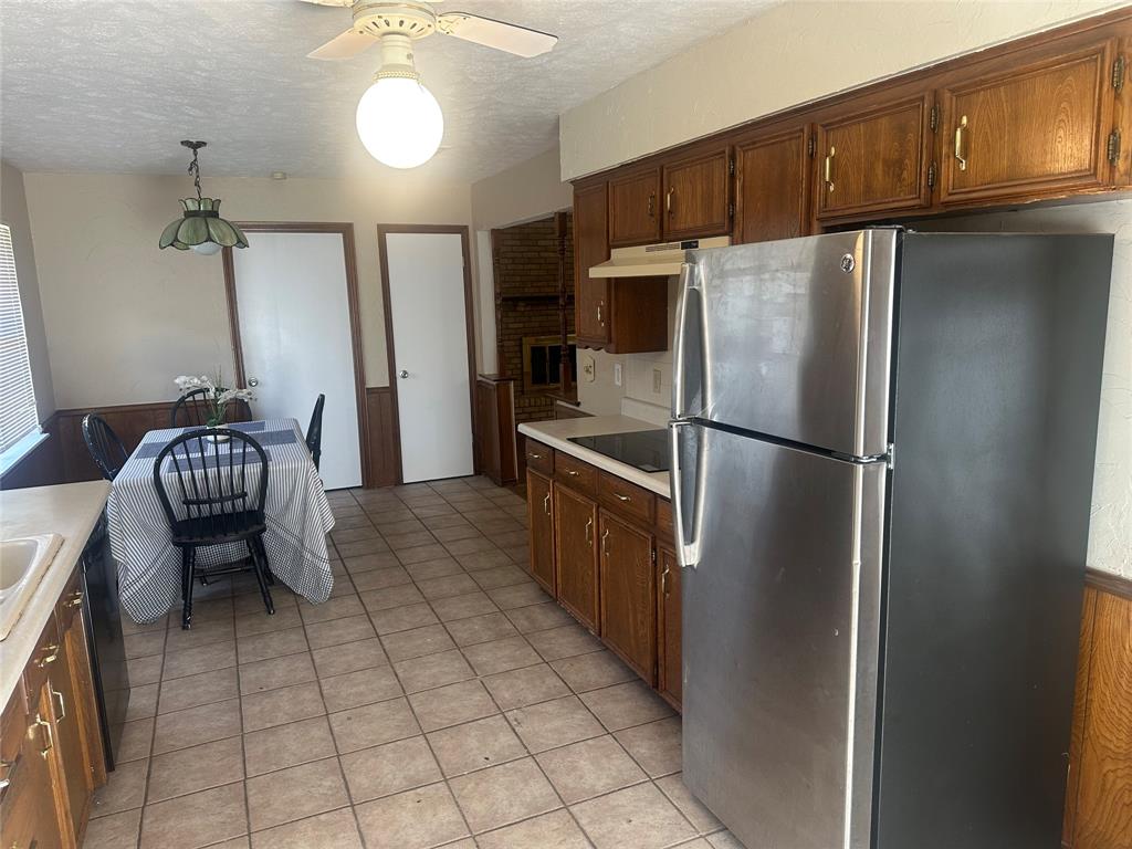 Kitchen featuring wood cabinetry, stainless steel refrigerator, tile flooring, and integrated lighting fixtures