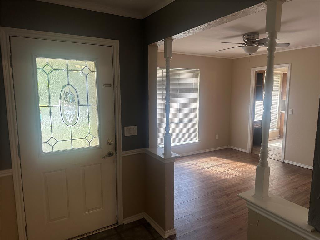 Entryway featuring a solid door with decorative glass paneling, wood-finish flooring, and white spindle columns on a half-wall partition