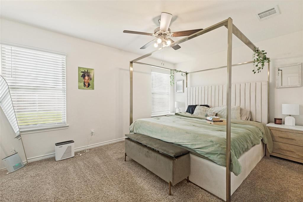 Neutral-toned wall-to-wall carpeting, dual windows with horizontal blinds, and a ceiling-mounted light fixture with a fan