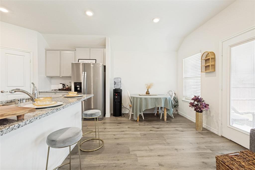 Kitchen featuring stone-finish countertops, stainless steel refrigerator, neutral cabinetry, recessed lighting, and wood-finish flooring
