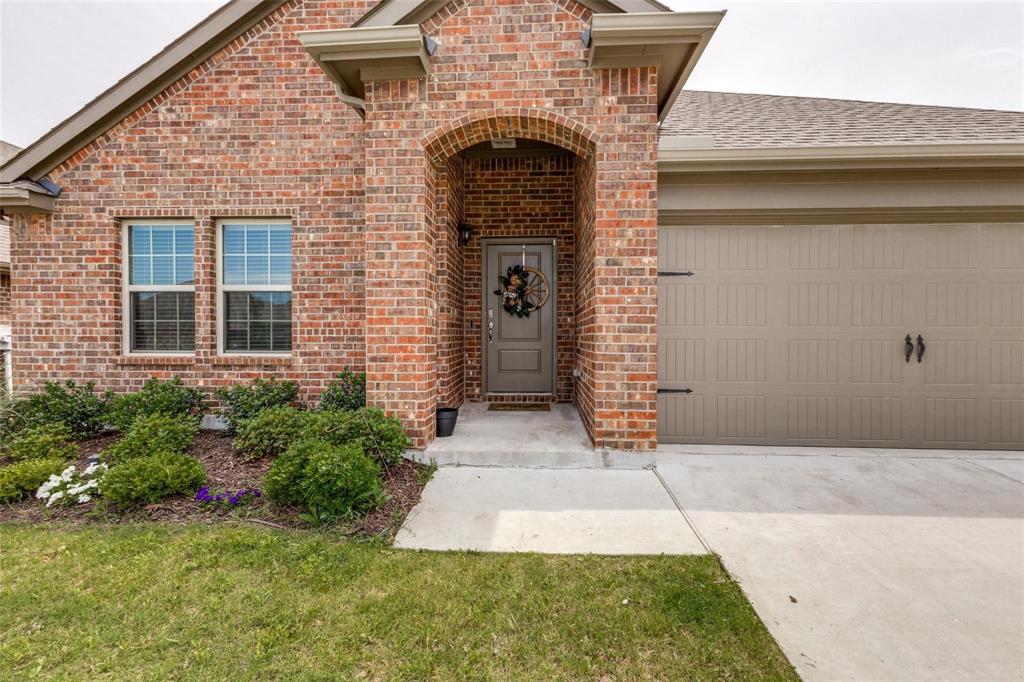 Brick exterior featuring an arched entryway, recessed porch, multi-pane windows, and a multi-panel garage door