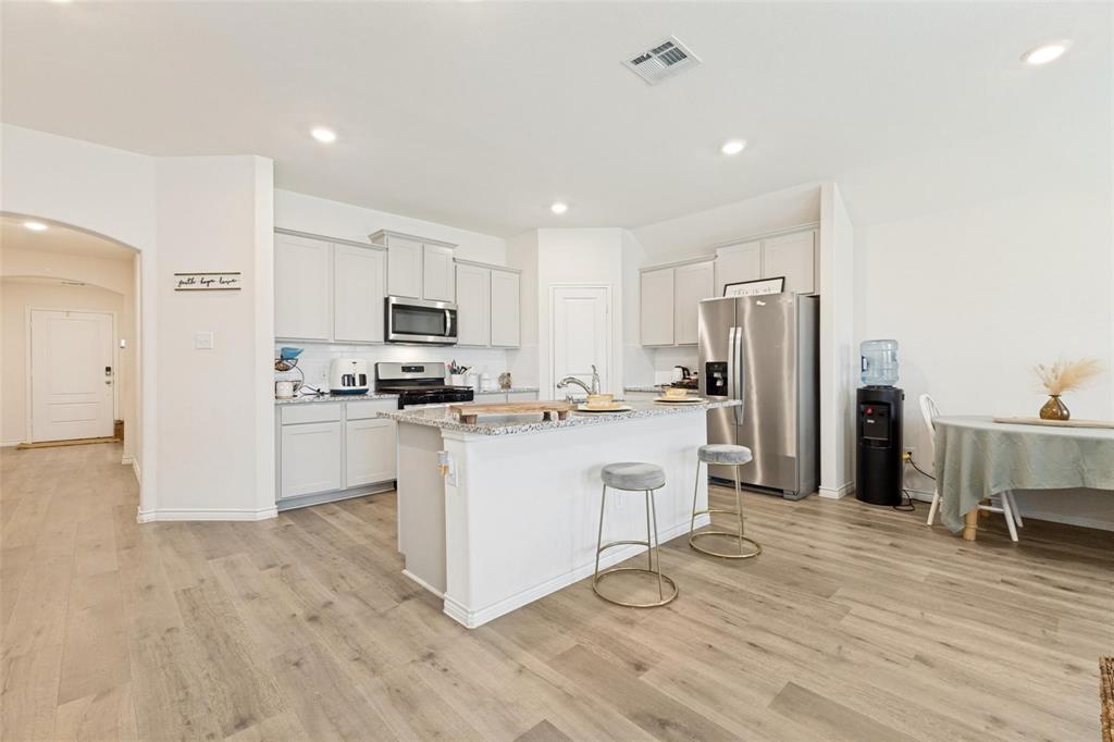Kitchen featuring a central island with a stone-finish countertop, light-toned cabinetry, recessed lighting, and wood-finish flooring