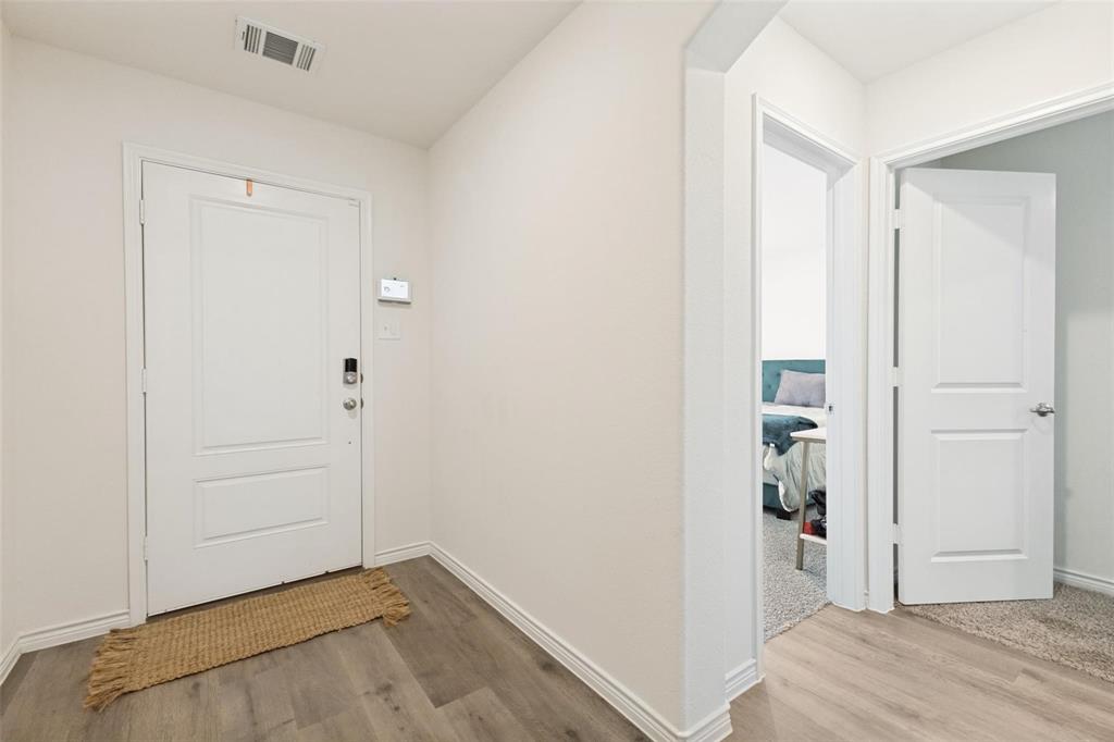 Entryway featuring wood-finish flooring, a paneled door with integrated electronic lock, and crisp white interior trim