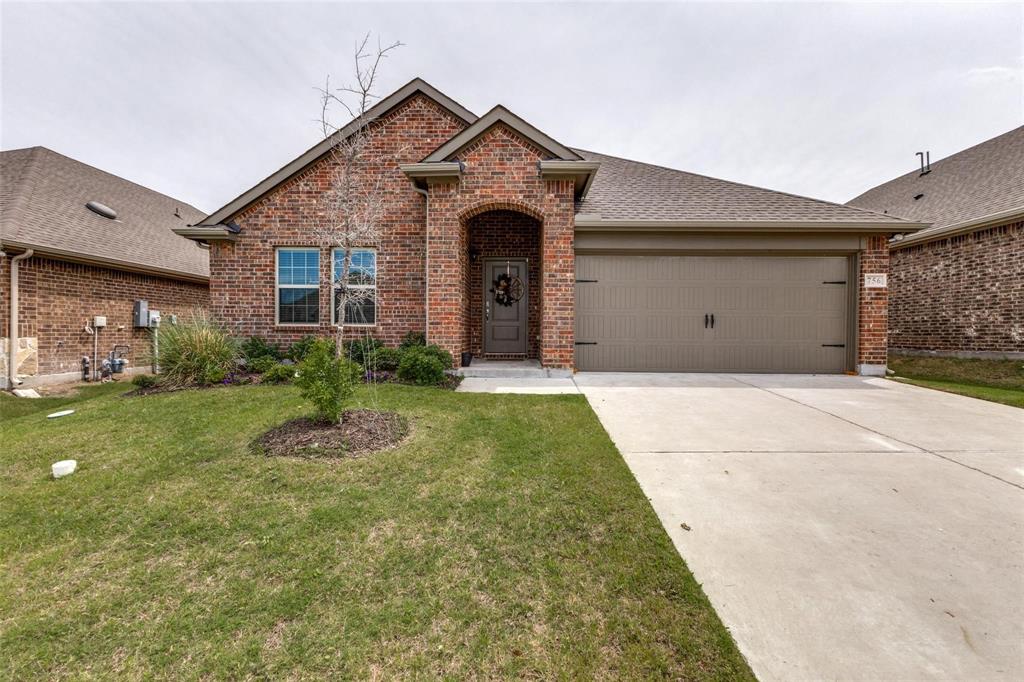 Traditional brick exterior featuring a multi-gable roofline, arched covered entryway, double-car garage, and concrete driveway
