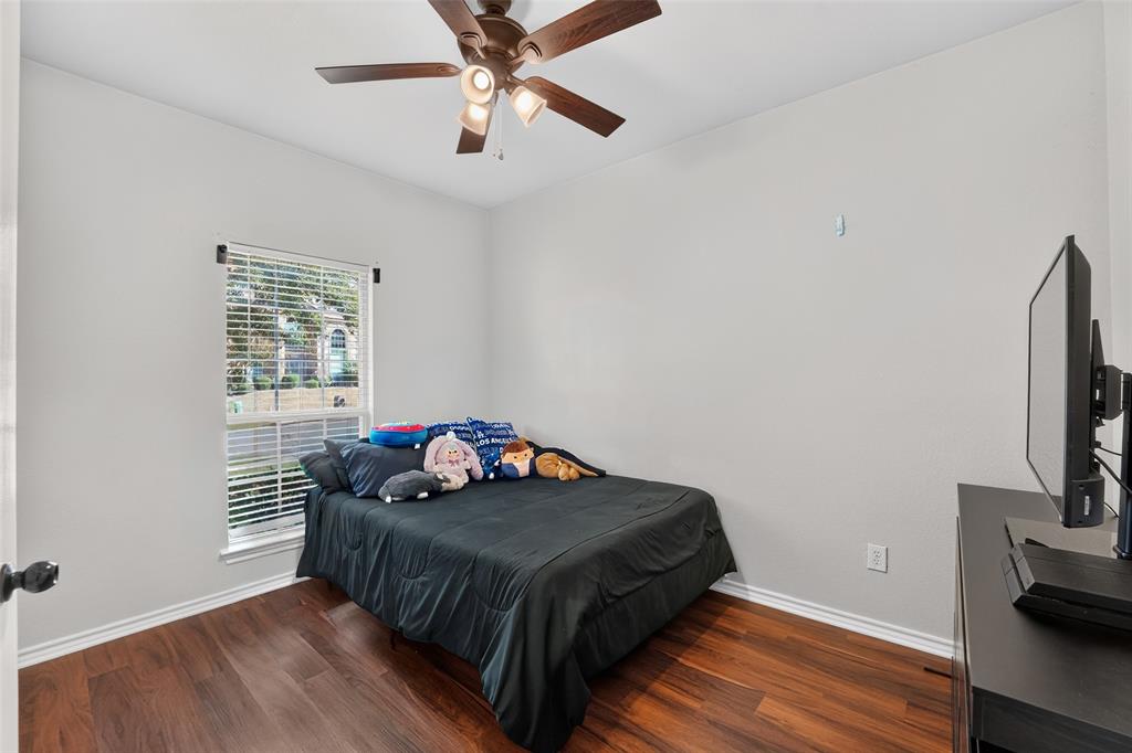 Room featuring wood-finish flooring, a neutral wall color palette, a single-pane window, and a ceiling fan with integrated lighting