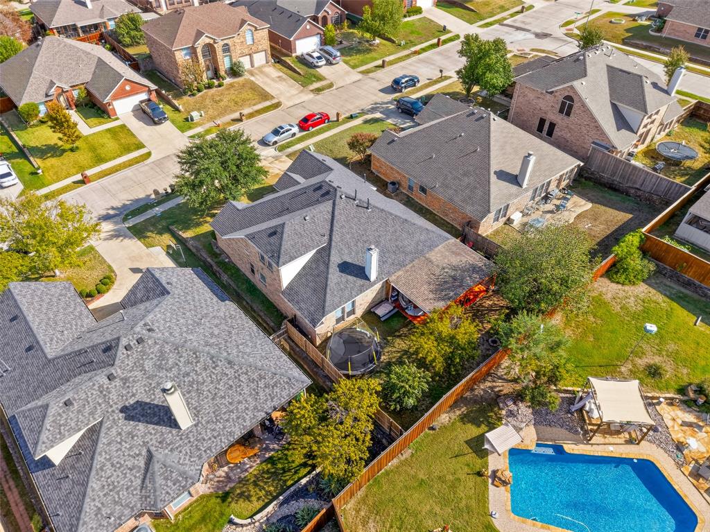 Aerial perspective featuring a shingled roofline, exterior chimney, and a private backyard with an in-ground swimming pool, stone patio, and wood fencing