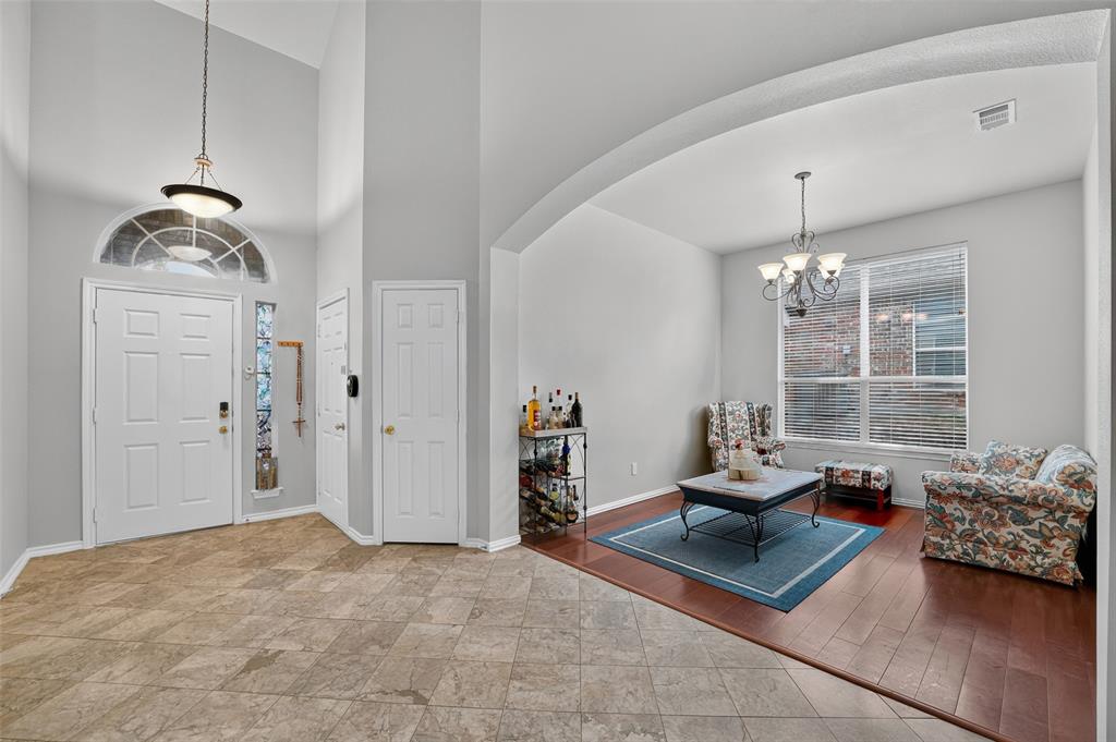 Foyer featuring soaring ceilings, a decorative transom window, natural stone-style tile flooring, wood-finish flooring, and an arched architectural opening