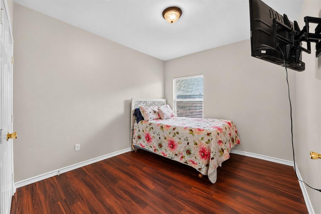 Room featuring wood-finish flooring, a single-pane window with horizontal blinds, and a flush-mount ceiling light fixture