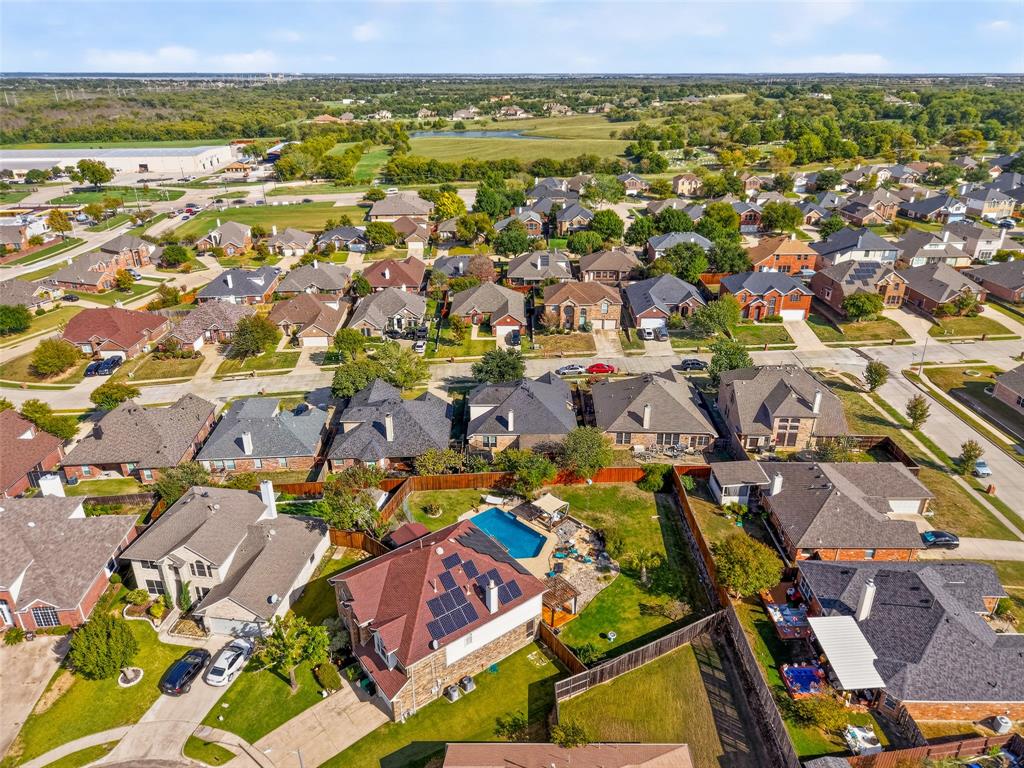 Aerial perspective of a residential property featuring an in-ground swimming pool, roof-mounted solar panels, brick and masonry siding, and a fenced backyard