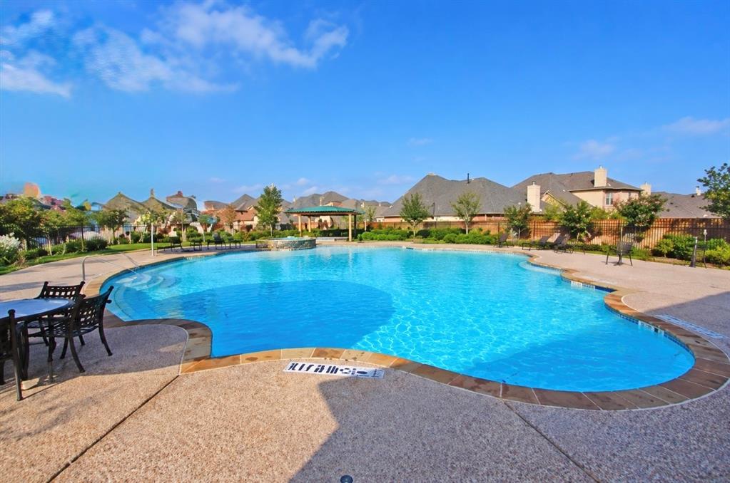 Swimming pool with stone-texture decking, integrated spa, and covered pergola