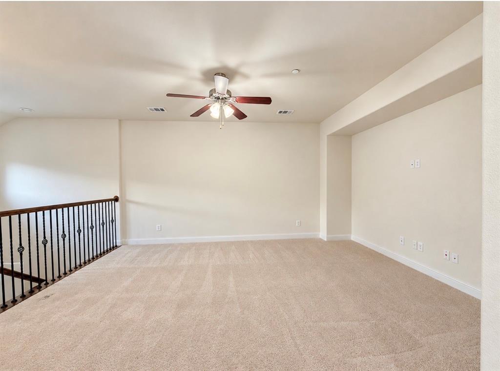 Open living area featuring wall-to-wall carpeting, high ceilings, a ceiling fan with integrated lighting, and a wrought-iron staircase railing