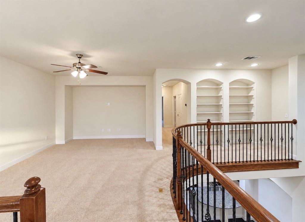 Curved balcony featuring metal balusters and a wood handrail, built-in recessed shelving, and integrated ceiling lighting