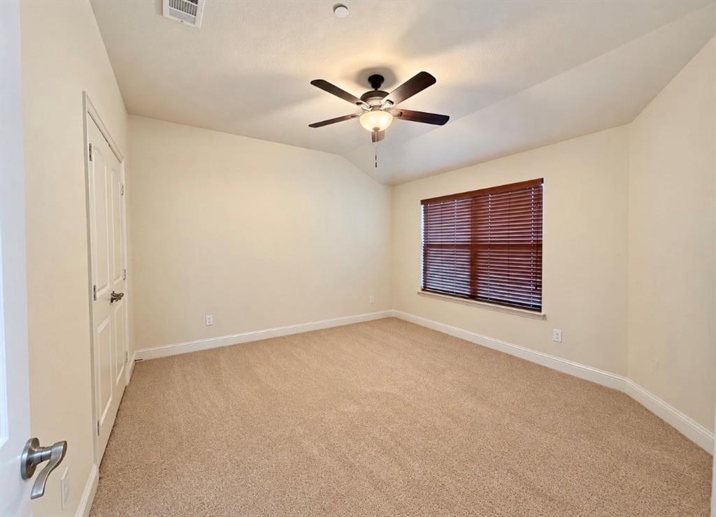 Room featuring vaulted ceilings, neutral wall tones, wall-to-wall carpeting, a ceiling fan with integrated light fixture, and window blinds