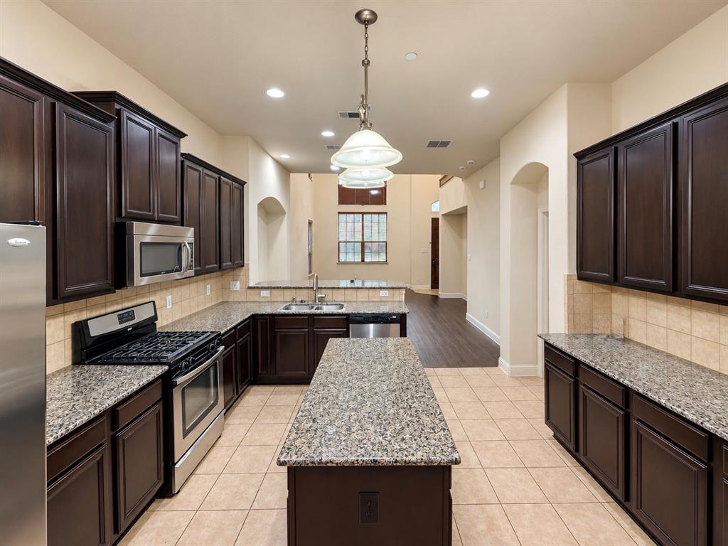 Kitchen featuring dark-finish cabinetry, stone countertops, a central island, stainless steel appliances, and tile flooring