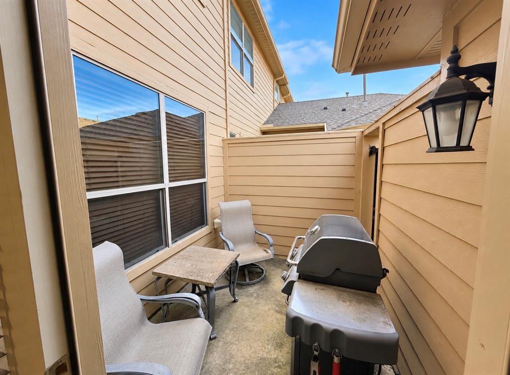 Private concrete patio featuring horizontal lap siding, a fenced enclosure, and an attached exterior wall-mounted lantern light