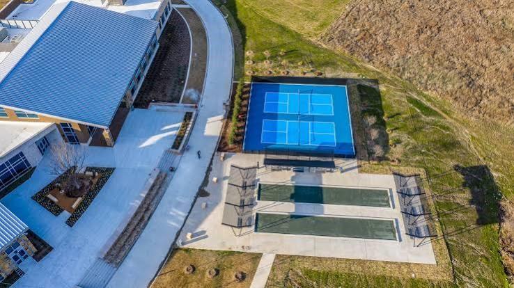 Recreational area featuring a dual pickleball court, two bocce ball courts, concrete hardscaping, and landscaped garden beds
