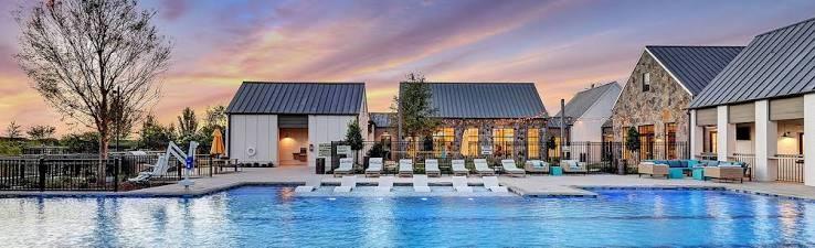 Swimming pool featuring a Baja shelf, stone and vertical siding exterior, metal roofing, and paved deck