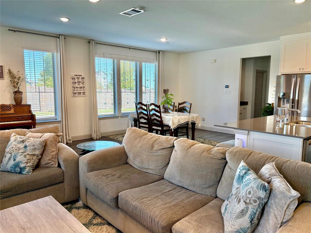 Open-concept living space featuring high ceilings with recessed lighting, large windows with natural illumination, and a kitchen island with stone-surface countertop