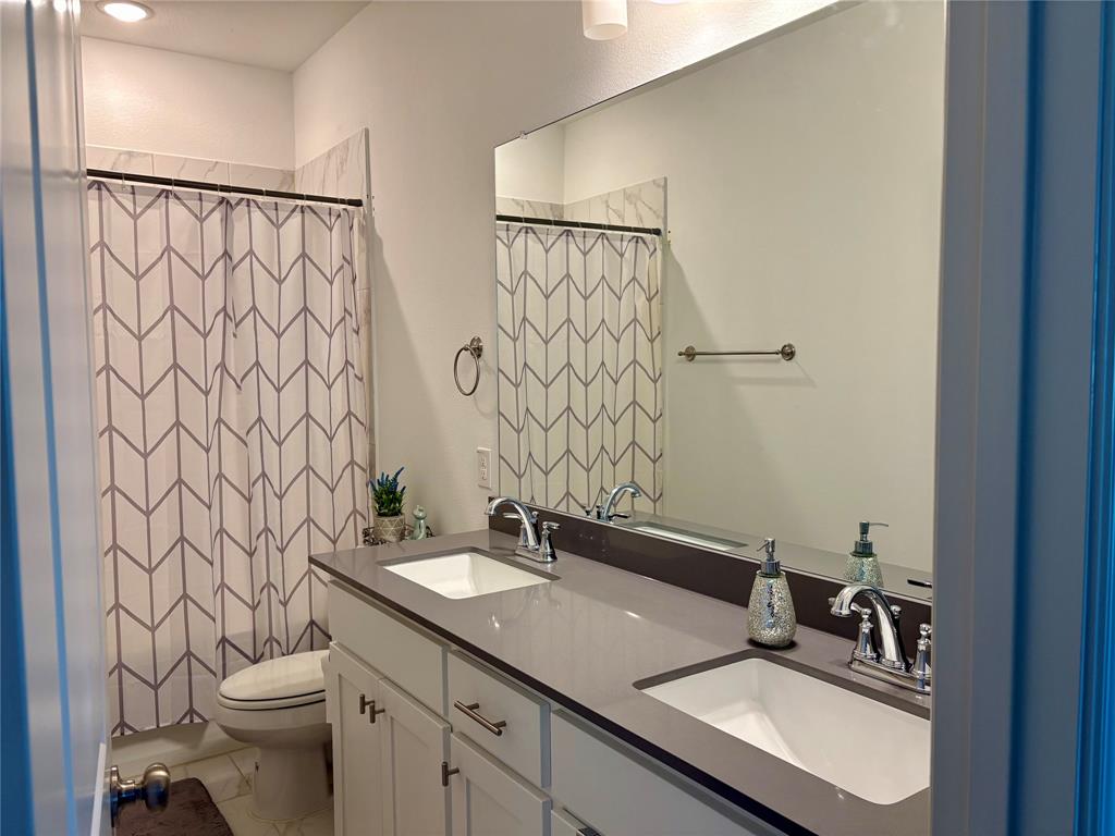 Dual-sink vanity with a solid-surface countertop, undermount sinks, and polished chrome fixtures paired with a full-width vanity mirror