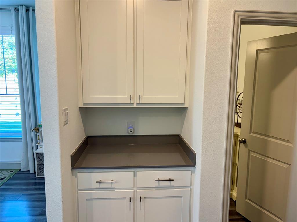 Built-in cabinetry featuring white shaker-style doors, matte hardware, and a solid-surface countertop with a matching backsplash
