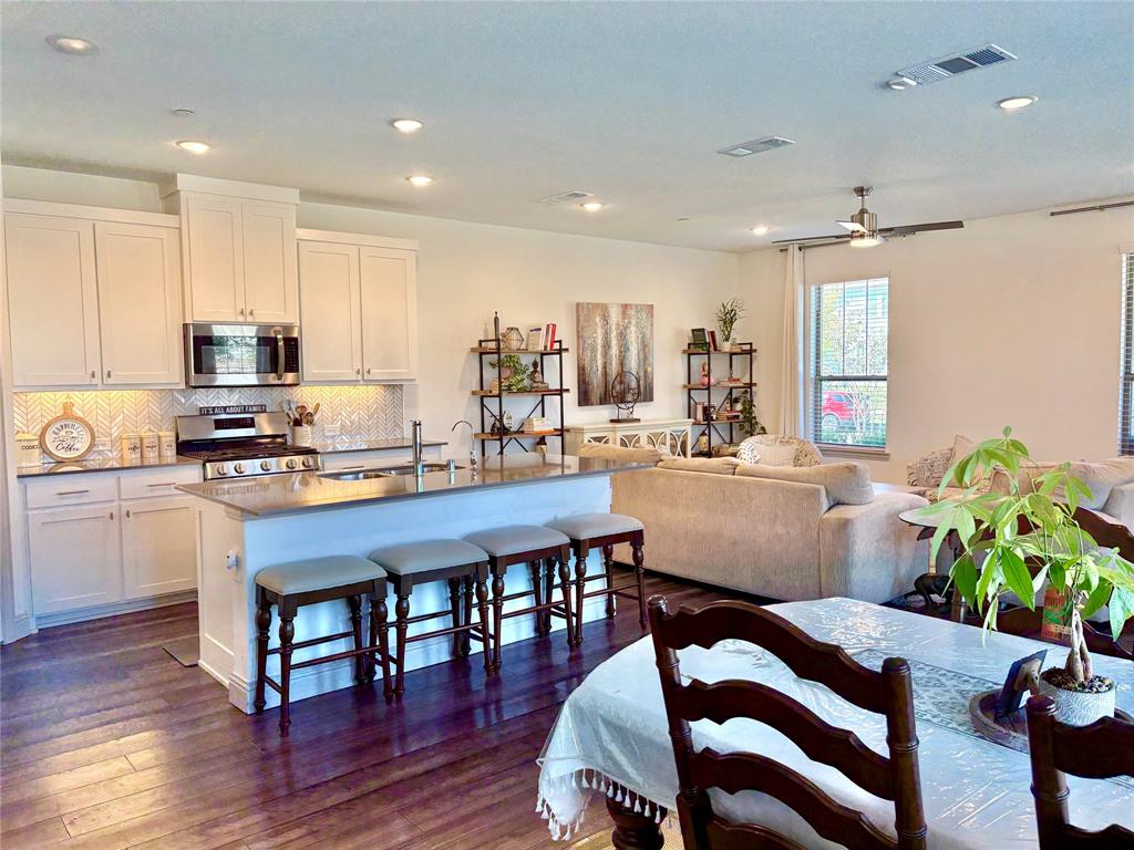 Kitchen featuring white shaker-style cabinetry, herringbone-pattern tile backsplash, stone countertops, central island with seating, and recessed lighting