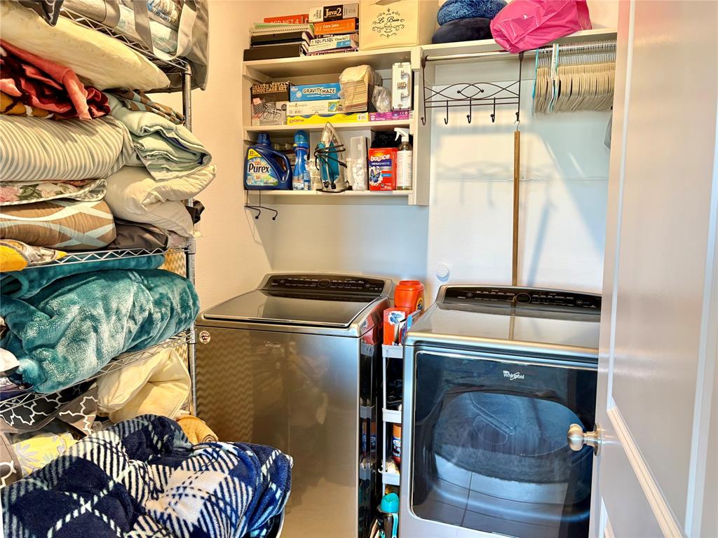 Laundry space featuring built-in white shelving, an integrated clothing rod with decorative hardware, and metallic finish appliance hookups